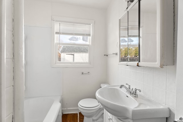 bathroom with a bathing tub, sink, toilet, tasteful backsplash, and wood-type flooring