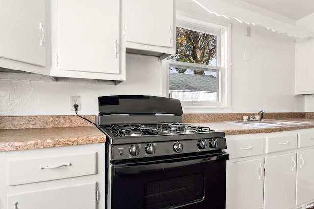 kitchen with black gas range oven, white cabinetry, and sink