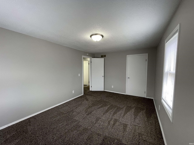 carpeted empty room featuring a textured ceiling