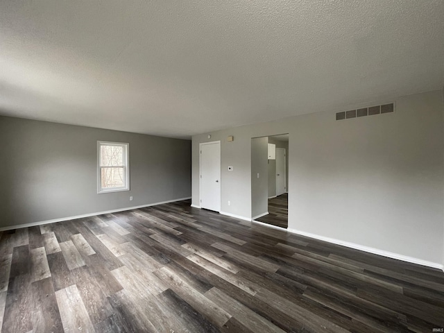 spare room featuring a textured ceiling and dark hardwood / wood-style floors