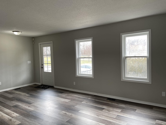 empty room with plenty of natural light, hardwood / wood-style floors, and a textured ceiling