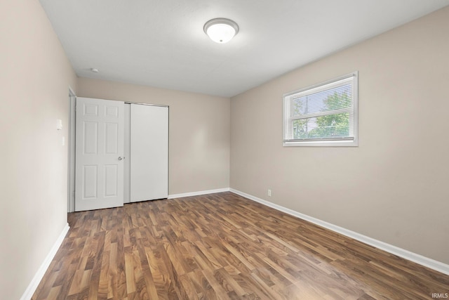 unfurnished bedroom with a closet and dark wood-type flooring