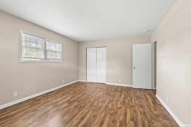 unfurnished bedroom featuring a closet and dark wood-type flooring