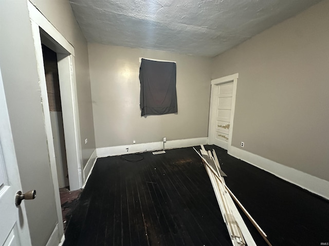 unfurnished room featuring wood-type flooring and a textured ceiling