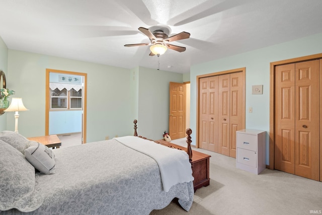 carpeted bedroom with ceiling fan and two closets