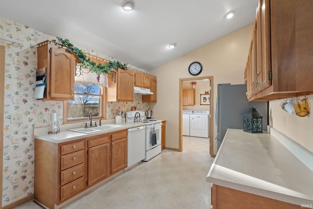 kitchen with washing machine and clothes dryer, white appliances, vaulted ceiling, and sink