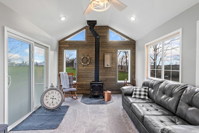 living room featuring high vaulted ceiling, a wealth of natural light, a wood stove, and wooden walls