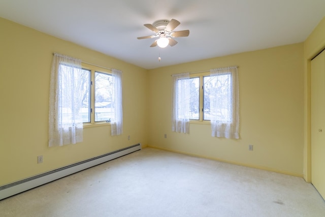 carpeted empty room with ceiling fan, a wealth of natural light, and a baseboard radiator