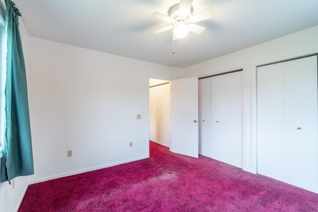 unfurnished bedroom with carpet, ceiling fan, and multiple closets