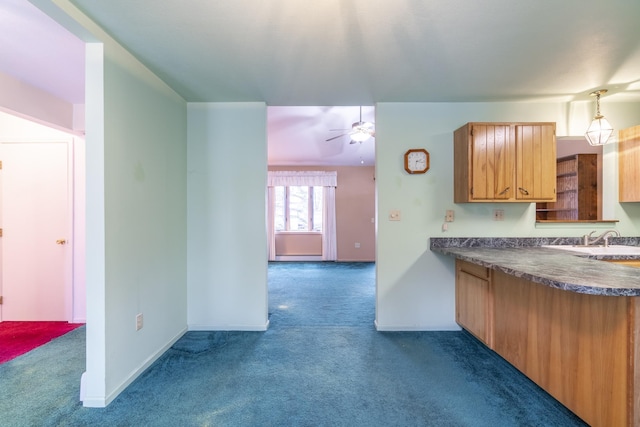 kitchen featuring sink, dark carpet, hanging light fixtures, and ceiling fan