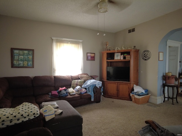 living room with ceiling fan, carpet floors, and a textured ceiling