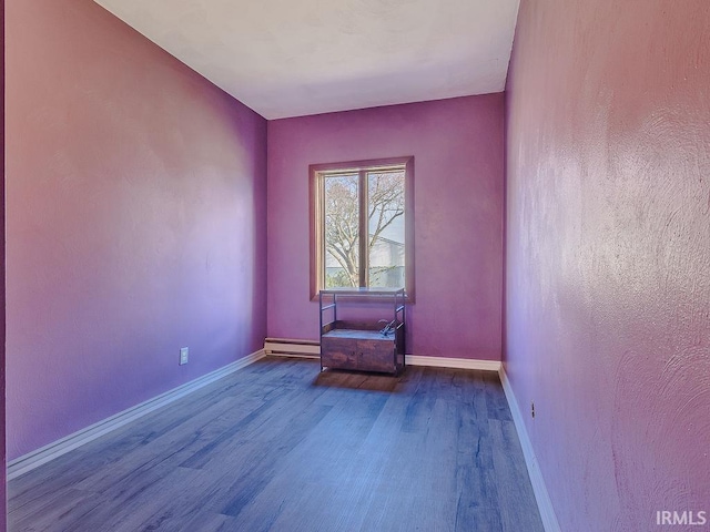 spare room featuring wood-type flooring and baseboard heating