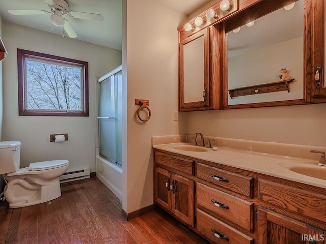 full bathroom with vanity, shower / bath combination with glass door, a baseboard heating unit, hardwood / wood-style flooring, and toilet