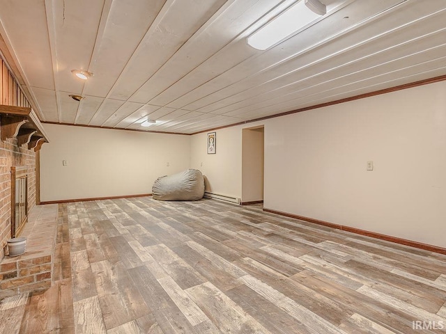 basement with crown molding, a fireplace, a baseboard radiator, and hardwood / wood-style flooring