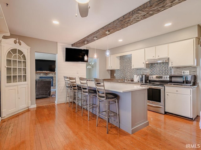 kitchen with beam ceiling, stainless steel appliances, white cabinetry, and light hardwood / wood-style flooring