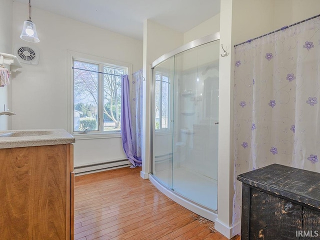 bathroom with vanity, a shower, wood-type flooring, and a baseboard radiator