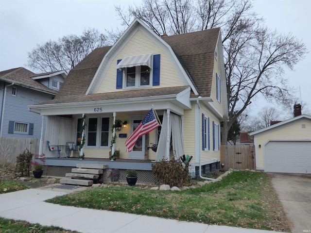 view of front of property featuring a porch, a garage, and an outbuilding