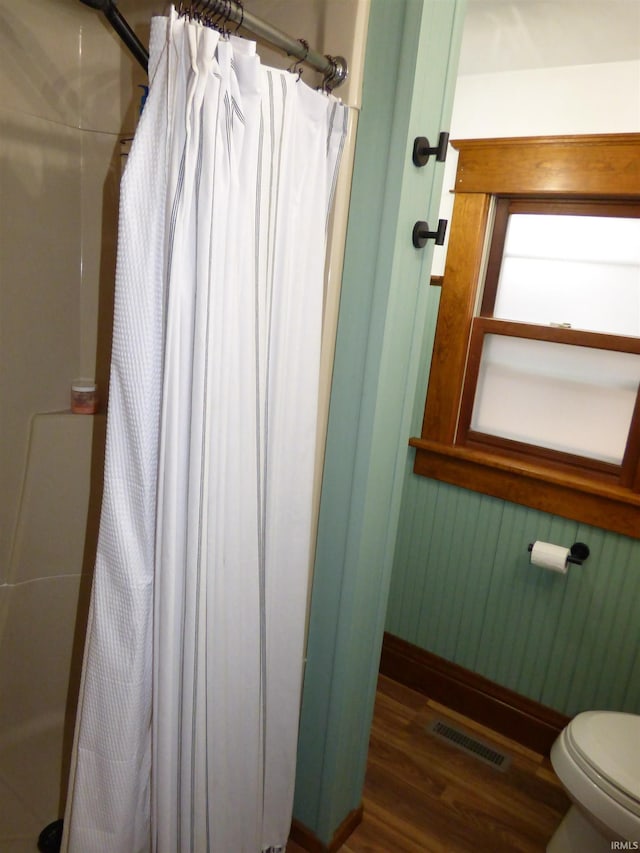 bathroom featuring curtained shower, wood-type flooring, and toilet