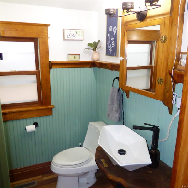 bathroom with hardwood / wood-style flooring, toilet, wood walls, and sink