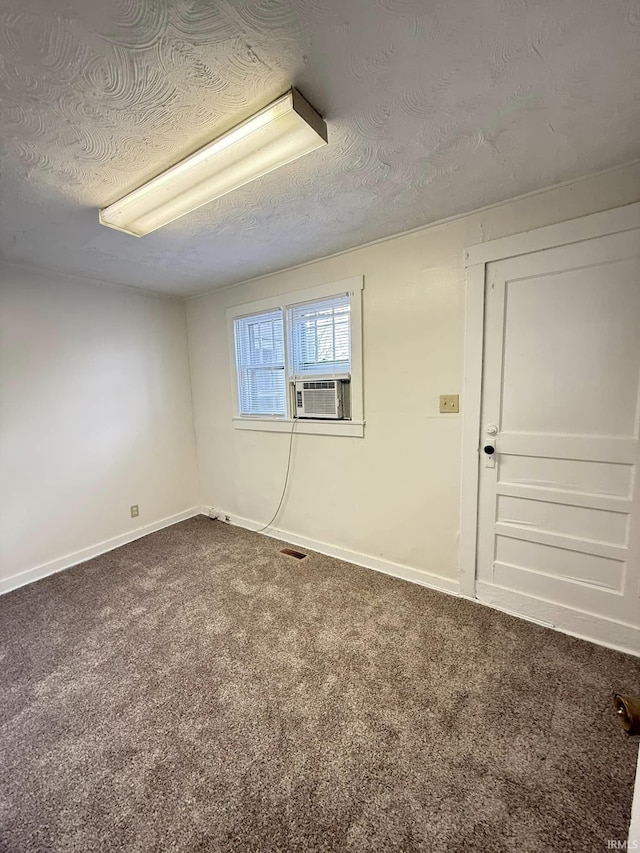 carpeted spare room with cooling unit and a textured ceiling