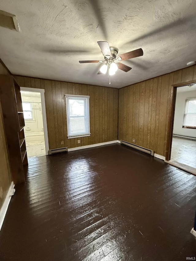 spare room featuring ceiling fan, dark hardwood / wood-style floors, and a baseboard heating unit