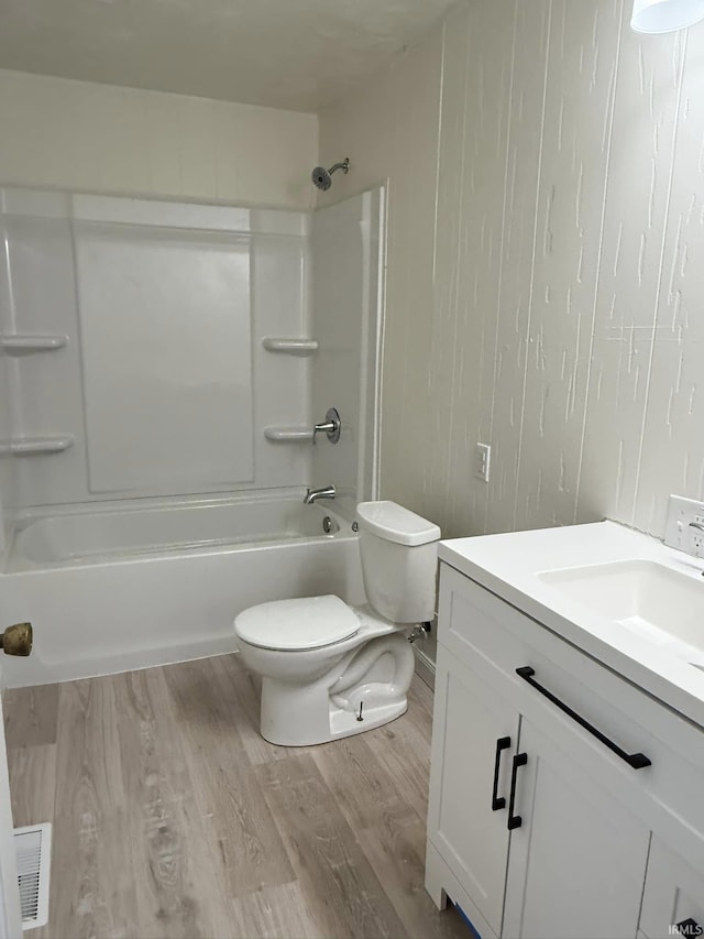 full bathroom with vanity, washtub / shower combination, wood-type flooring, and toilet