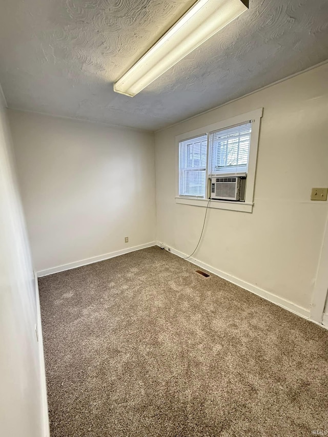 unfurnished room with cooling unit, carpet floors, and a textured ceiling