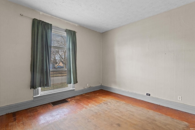 spare room with hardwood / wood-style floors, a healthy amount of sunlight, and a textured ceiling