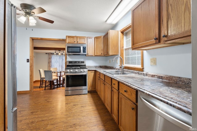 kitchen with appliances with stainless steel finishes, light wood-type flooring, ceiling fan, and sink