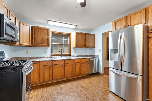 kitchen featuring a textured ceiling, sink, stainless steel appliances, and light hardwood / wood-style flooring