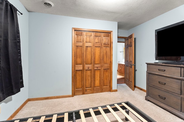 carpeted bedroom with a textured ceiling and a closet