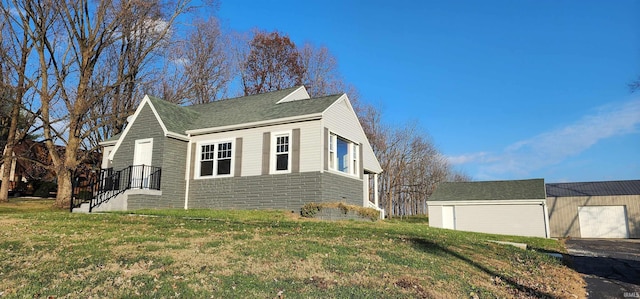 view of front of house featuring a garage, an outbuilding, and a front lawn