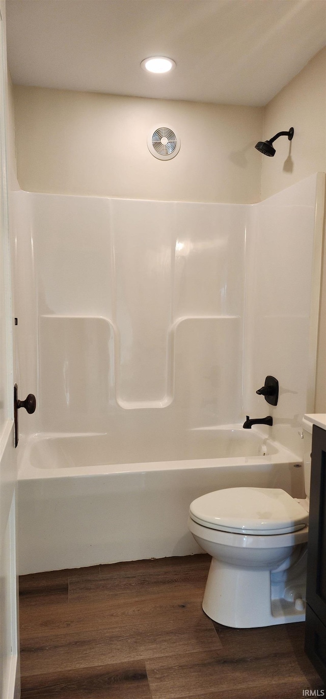 full bathroom with hardwood / wood-style floors, vanity, shower / bathtub combination, and toilet