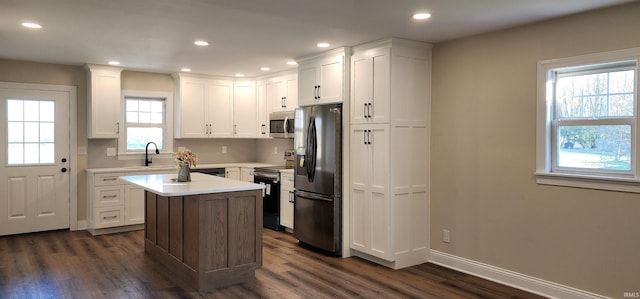 kitchen with sink, dark hardwood / wood-style floors, appliances with stainless steel finishes, a kitchen island, and white cabinetry