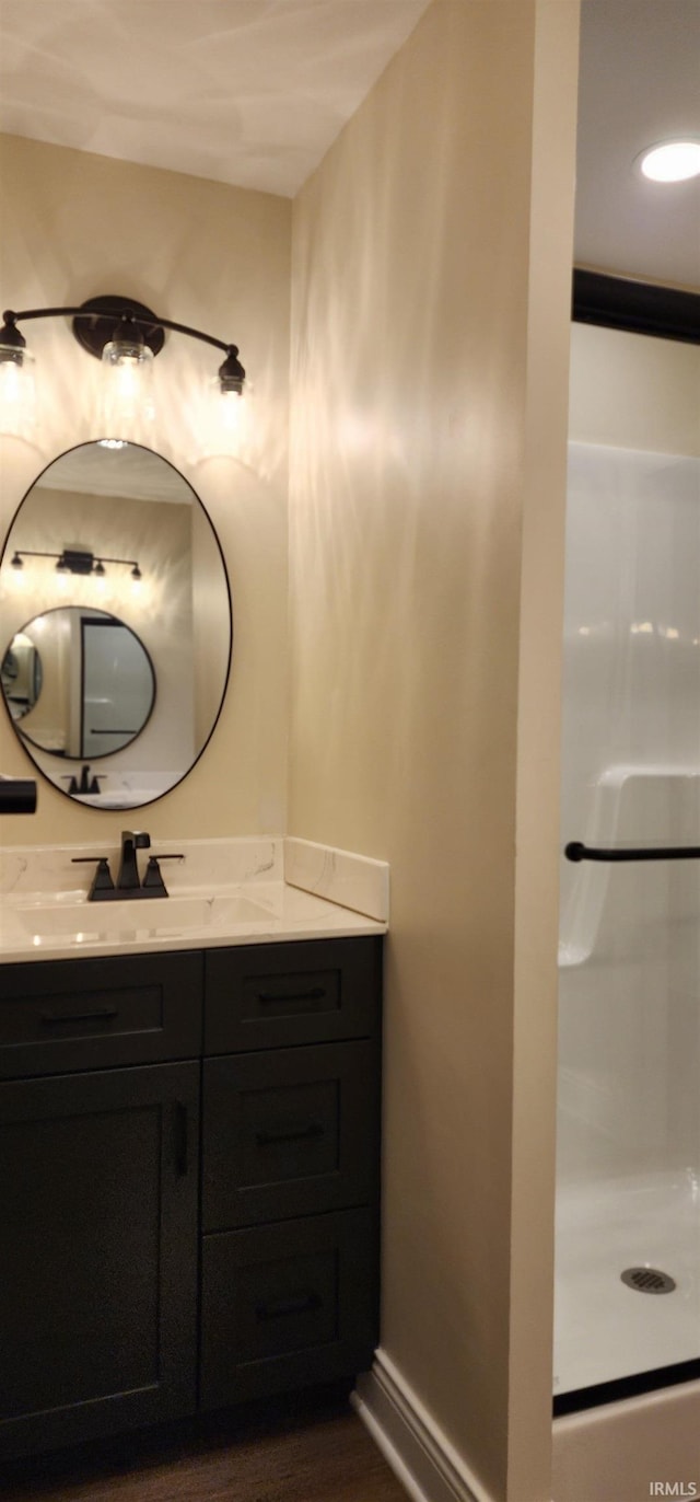 bathroom featuring hardwood / wood-style flooring, vanity, and walk in shower