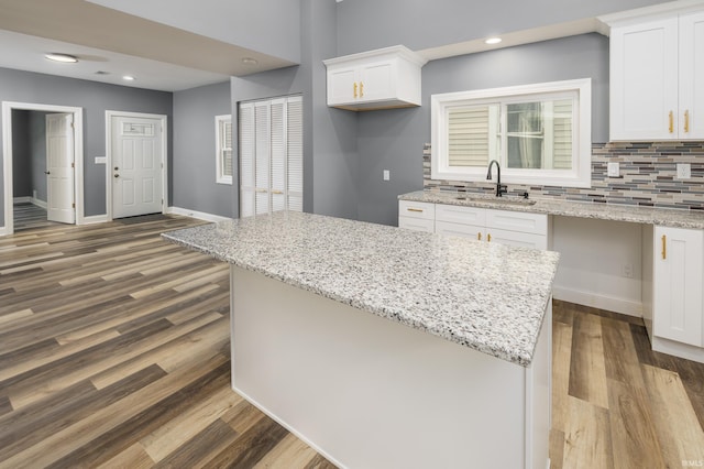 kitchen with light stone countertops, sink, white cabinets, and dark wood-type flooring