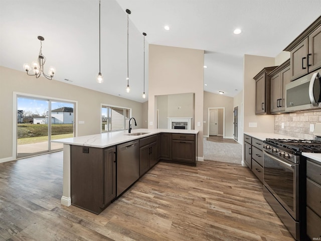 kitchen with hanging light fixtures, appliances with stainless steel finishes, dark brown cabinets, and wood-type flooring