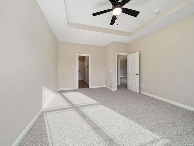 unfurnished bedroom with carpet flooring, ceiling fan, and a tray ceiling