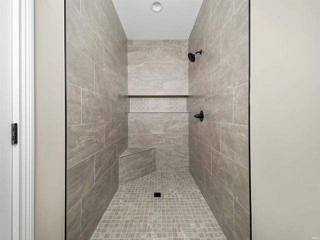 bathroom with a tile shower and a textured ceiling