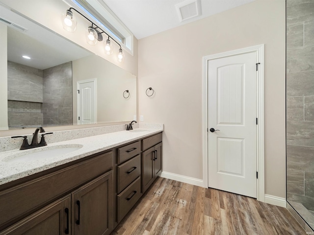 bathroom featuring vanity, wood-type flooring, and tiled shower