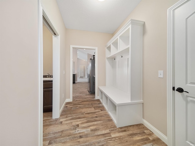 mudroom with light hardwood / wood-style floors, sink, and a textured ceiling