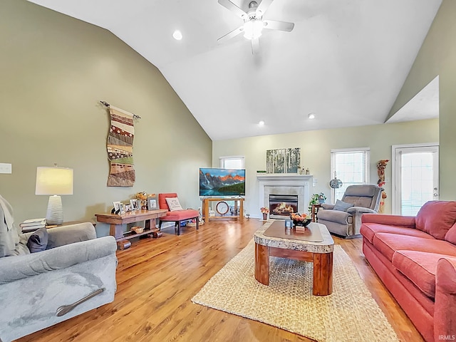 living room with a tiled fireplace, ceiling fan, hardwood / wood-style floors, and lofted ceiling