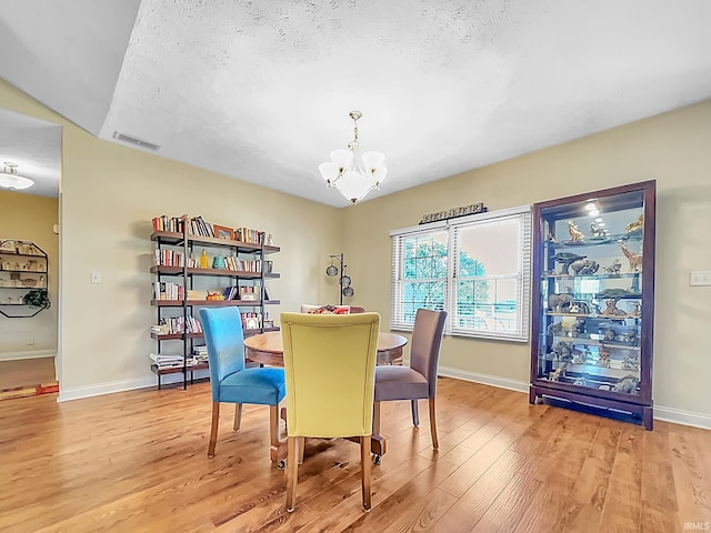 dining area featuring a chandelier, a textured ceiling, and light hardwood / wood-style flooring