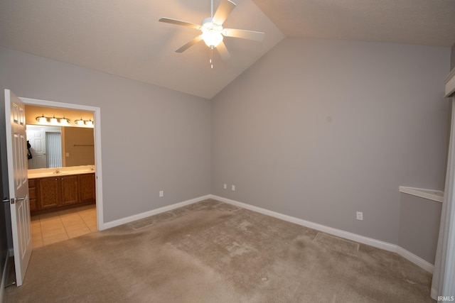 unfurnished bedroom with ceiling fan, lofted ceiling, connected bathroom, and light colored carpet