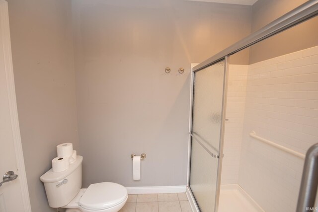 bathroom featuring toilet, tile patterned flooring, and a shower with door