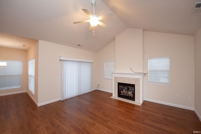 unfurnished living room with ceiling fan, vaulted ceiling, dark wood-type flooring, and a tile fireplace