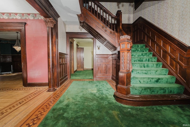 stairs with beam ceiling, carpet floors, and decorative columns