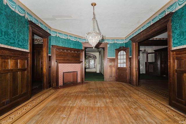 interior space with wooden walls, wood-type flooring, a notable chandelier, and ornamental molding