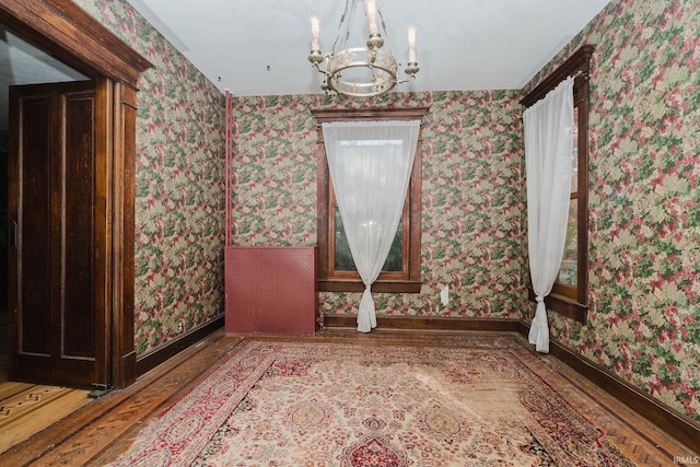 unfurnished room with an inviting chandelier and hardwood / wood-style flooring