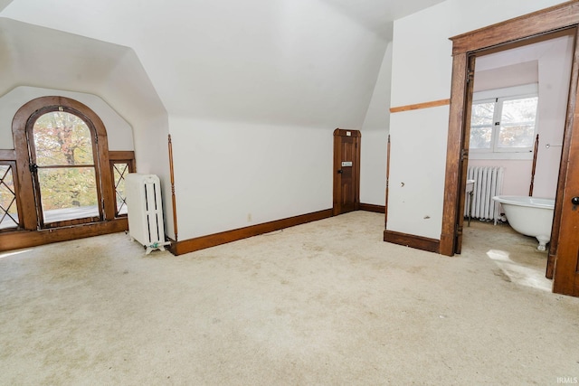 bonus room featuring radiator, a wealth of natural light, light colored carpet, and lofted ceiling